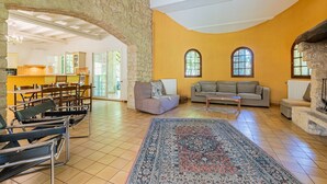 A spacious living area with a stone archway, a large rug, and a sofa. - Le Mas des Trois Sources - Grand jardin (Gignac)