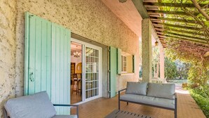 An outdoor patio with two grey sofas and a small table, a wooden pergola, and a view of a garden. - Le Mas des Trois Sources - Grand jardin (Gignac)