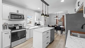 A modern kitchen with white cabinetry, stainless steel appliances, and a central island. - Spacious 3 Bdrm Haven - Steps to Downtown Ch'town (Charlottetown)