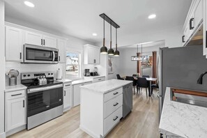 A modern kitchen with white cabinetry, stainless steel appliances, and a central island. - Spacious 3 Bdrm Haven - Steps to Downtown Ch'town (Charlottetown)
