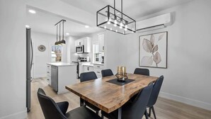 A modern kitchen with white cabinets, a wooden dining table, and black chairs. - Spacious 3 Bdrm Haven - Steps to Downtown Ch'town (Charlottetown)