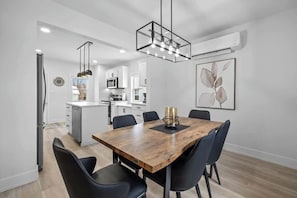 A modern kitchen with white cabinets, a wooden dining table, and black chairs. - Spacious 3 Bdrm Haven - Steps to Downtown Ch'town (Charlottetown)