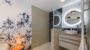 Ein modernes Badezimmer mit Dusche, Waschbecken und Spiegel.