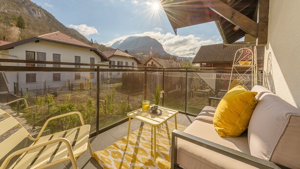 Ein Balkon mit einer Couch, einem kleinen Tisch und einem gelben Teppich mit Muster.
