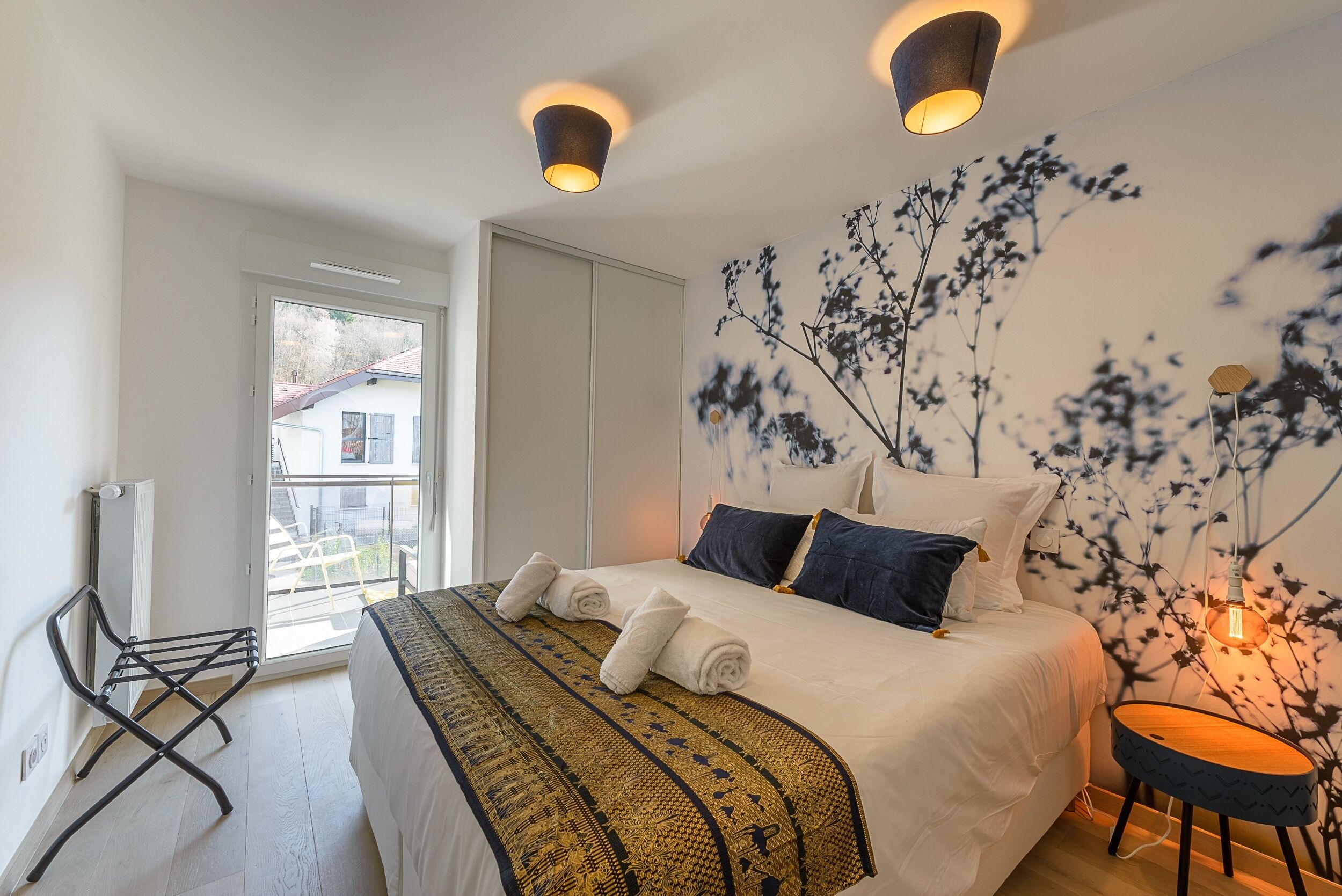 A bedroom with a bed, a wall-mounted lamp, a radiator, and a window.