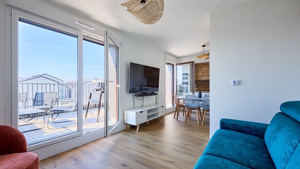 Un soggiorno moderno con una TV, un divano blu e un'area pranzo con tavolo e sedie.