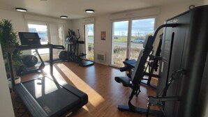 Una palestra privata con tapis roulant, ellittica e macchina per pesi, ampie finestre e vista sull'esterno.