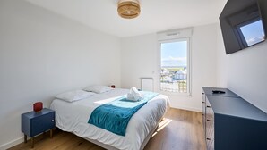 Camera da letto con un letto, un comodino, una cassettiera, una finestra con vista e una lampada a sospensione al soffitto.