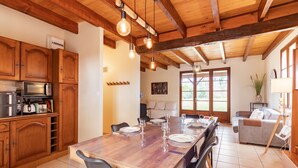 A wooden kitchen with a dining table set for six, a microwave, and a coffee maker. - L'Oasis de SaBen - Piscine Privée (Belfort-du-Quercy)