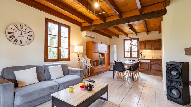 A living room with a sofa, coffee table, and a clock on the wall. - L'Oasis de SaBen - Piscine Privée (Belfort-du-Quercy)