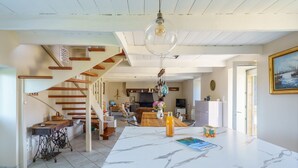 Una cocina amplia con encimera de mármol, una escalera de madera y un comedor con mesa y sillas.