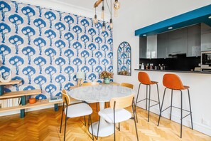 Ruokailutila, jossa on pyöreä pöytä, tuolit ja kuviollinen tapetti.