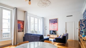 A modern living room with a marble table, dark sofas, and a large window. - Grands Boulevards Home (Paris)