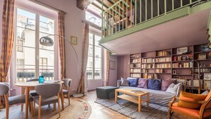 A cozy living room with a sofa, coffee table, and bookshelves. - Saint Michel Seine Loft (Paris)