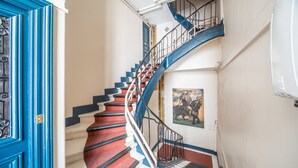 A spiral staircase with red steps and a blue railing, leading to an upper floor. - Saint Michel Seine Loft (Paris)