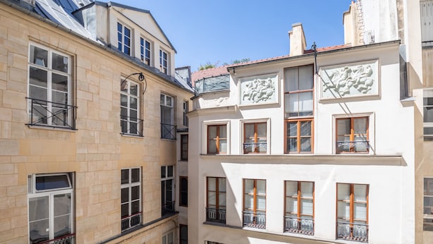 A multi-story building with stone and plaster facades, multiple balconies, and a clear sky. - Saint Michel Seine Loft (Paris)
