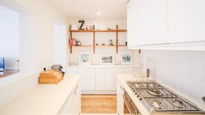 Een moderne keuken met witte kastjes, een houten plank met ingelijste foto's, en een gasfornuis.