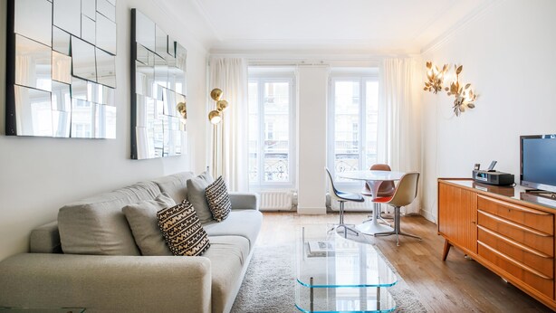 Een moderne woonkamer met een bank, salontafel en een televisie op een houten kast.