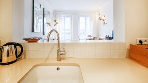 Een moderne keuken met een spoelbak, waterkoker en raam met uitzicht op een balkon.
