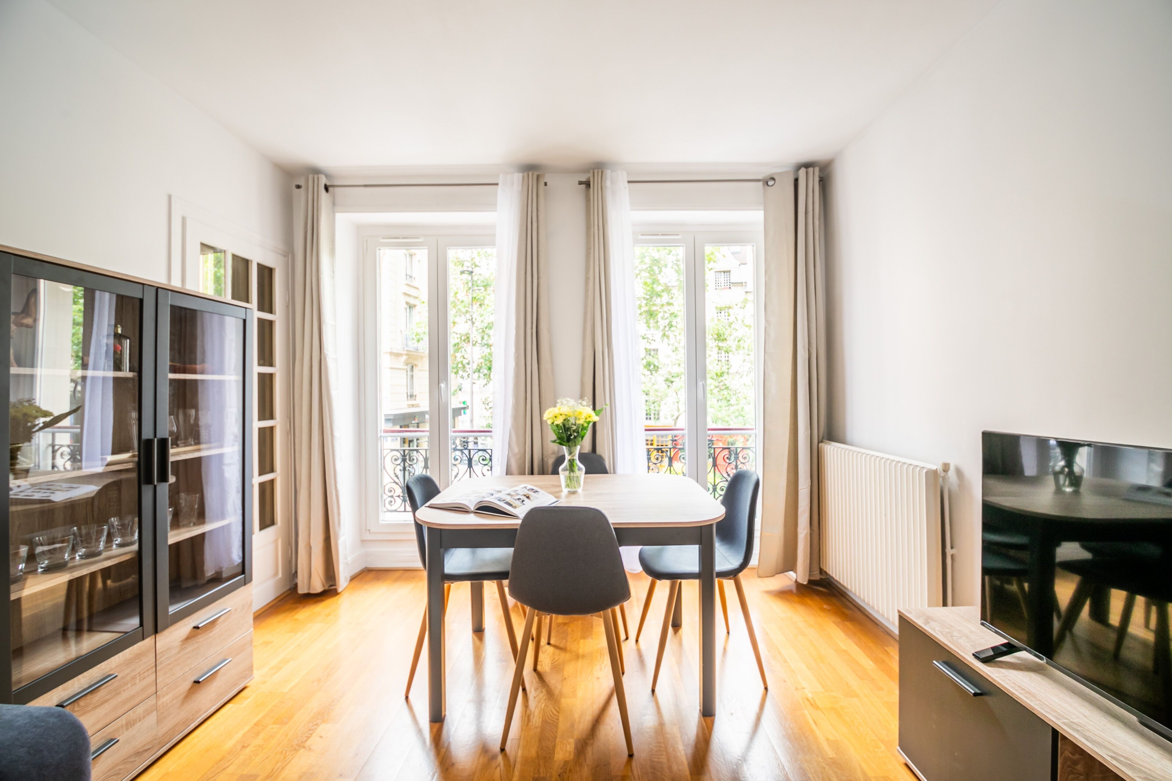 A dining area with a table, chairs, a cabinet, and a TV.