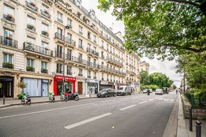 A street with buildings, a red storefront, and parked vehicles. - Quartier Latin Sorbonne (Paris)