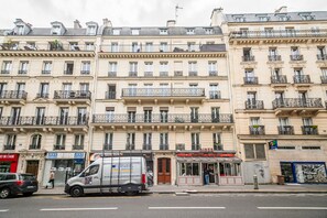 A multi-story building with balconies, a parked van, and storefronts including a diner and video game store. - Quartier Latin Sorbonne (Paris)
