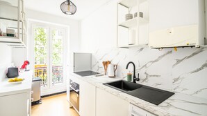 Eine moderne Küche mit Marmorarbeitsplatte, einer schwarzen Spüle und einem eingebauten Backofen.