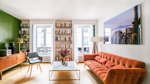 A living room with a sofa, a coffee table, a bookshelf, and a painting on the wall. - Bonne Nouvelle Cosy - One Bedroom Apartment, Sleeps 2 (Paris)