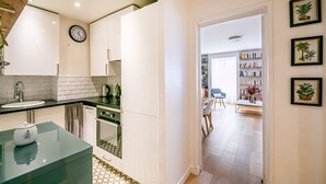 A modern kitchen with white cabinets, a sink, and a clock on the wall. - Bonne Nouvelle Cosy - One Bedroom Apartment, Sleeps 2 (Paris)