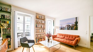 A living room with a sofa, a coffee table, a chair, and bookshelves. - Bonne Nouvelle Cosy - One Bedroom Apartment, Sleeps 2 (Paris)