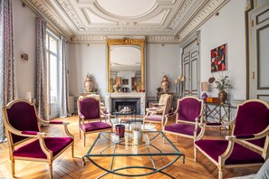 A room with a fireplace, ornate furniture, and a large mirror. - Wagram Luxury Palace (Paris)