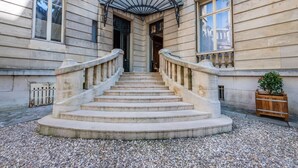 A grand entrance with a stone staircase leading to a door, flanked by two windows and a decorative fan.