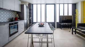 A modern kitchen with a dining table, chairs, a TV, and a sofa. - Tour Eiffel Loft - One Bedroom Apartment, Sleeps 3 (Paris)