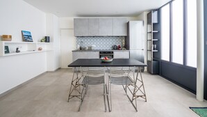 A modern kitchen with a black countertop, two metal chairs, and a bowl of fruit. - Tour Eiffel Loft - One Bedroom Apartment, Sleeps 3 (Paris)