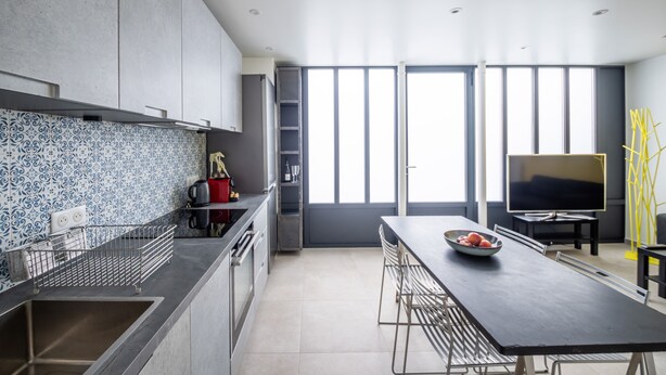 A modern kitchen with a dining area, large windows, and a flat-screen TV. - Tour Eiffel Loft - One Bedroom Apartment, Sleeps 3 (Paris)