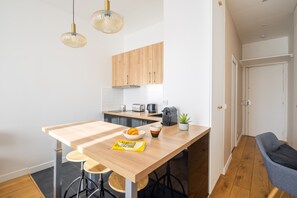 Eine kleine Küche mit Holzschränken, einem Barhocker, einer Kaffeemaschine und einem kleinen Topfpflanzen.