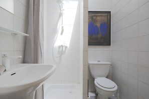 Ein Badezimmer mit Waschbecken, Toilette, Dusche und einem gerahmten Kunstwerk an der Wand.
