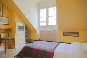 Ein Schlafzimmer mit einem Bett, einem Sessel, einer Heizung und einem Fenster.