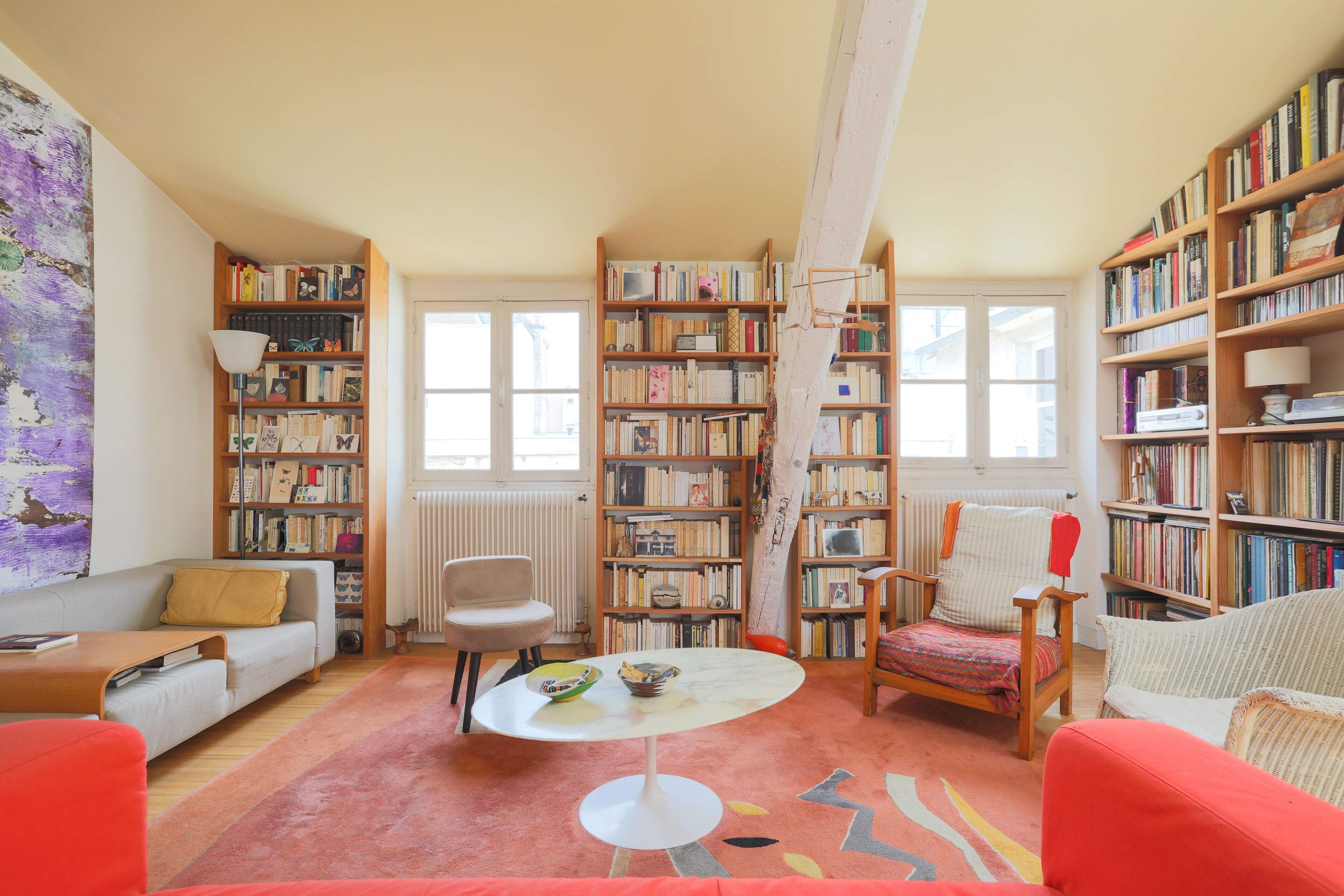 A cozy living room with a sofa, armchairs, a coffee table, and a bookshelf filled with books.