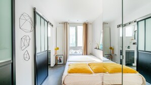 Una habitación de hotel moderna con cama, un espejo grande y arte mural geométrico.