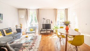 Una sala de estar moderna con un sofá, televisor, mesa de comedor y sillas.