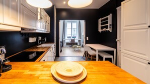 A modern kitchen with white cabinets, a wooden countertop, and pendant lighting. - Alma Tour Eiffel - One Bedroom Apartment, Sleeps 3 (Paris)