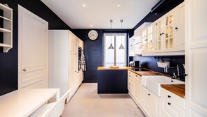 A modern kitchen with white cabinets, a wooden countertop, and a clock on the wall. - Alma Tour Eiffel - One Bedroom Apartment, Sleeps 3 (Paris)