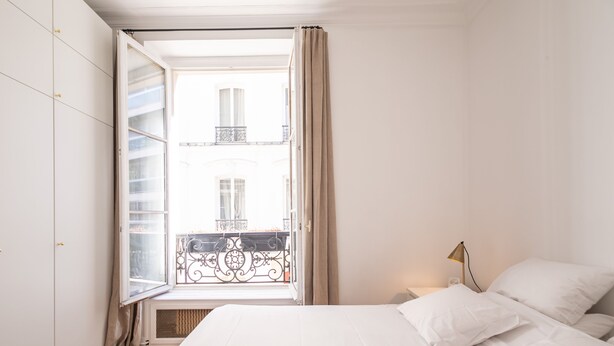 A bedroom with a bed, a window with curtains, a nightstand, and a lamp. - Alma Tour Eiffel - One Bedroom Apartment, Sleeps 3 (Paris)