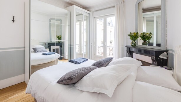 Ein Schlafzimmer mit einem großen Bett, einem Schminktisch, einem Spiegel und Blick auf einen Balkon.