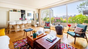 Ein moderner Wohnraum mit Küche, Essbereich und großzügigem Balkon mit Pflanzen.