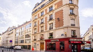 Ein mehrstöckiges Gebäude mit einem Restaurant im Erdgeschoss, einer Fußgängerüberweg und abgestellten Autos.
