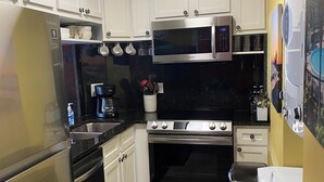 A compact kitchen with white cabinets, stainless steel appliances, and a microwave. - updated 2-bedroom, 2 bath, sleeps 6 family friendly condo. Many extras. (Gulf Shores)