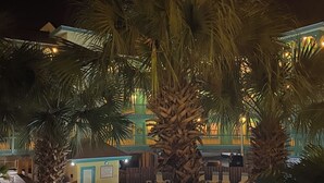 A nighttime pool area with palm trees, lounge chairs, and a building with illuminated windows in the background. - updated 2-bedroom, 2 bath, sleeps 6 family friendly condo. Many extras. (Gulf Shores)