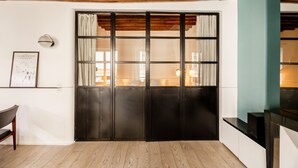 A room with a wooden ceiling, a black door with glass panels, a framed picture on the wall, and a wooden floor. - Île Saint Louis Cosy (Paris)